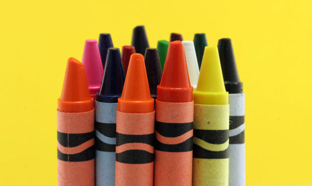Group of new crayons isolated against a yellow background.
