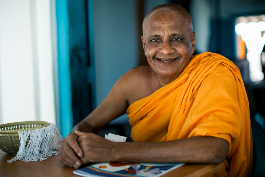 Portrait of elderly Asian buddhist monk smiling at camera in buddhist monastery at river in Madu Ganga, Sri Lanka.